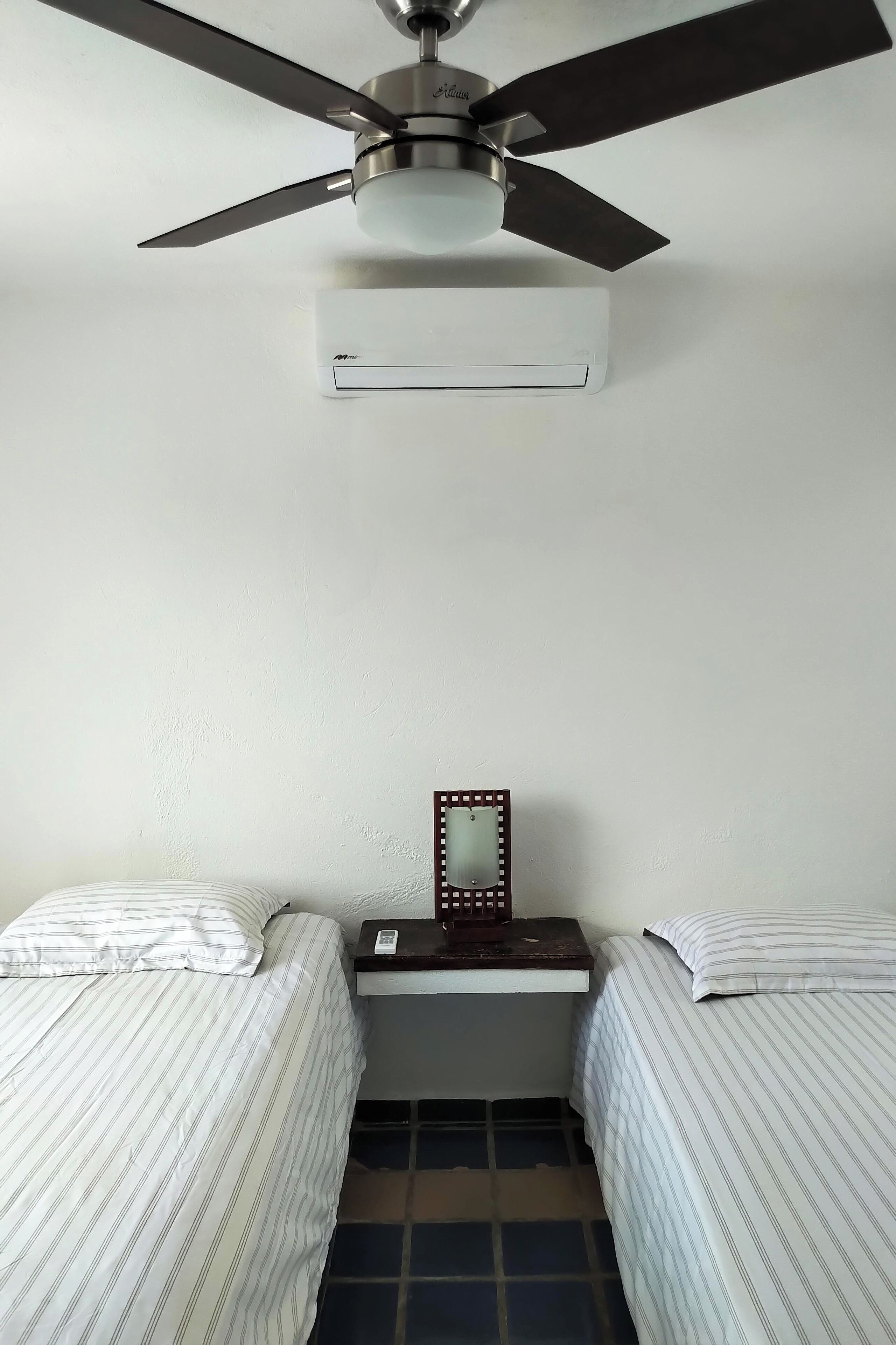 A room with two beds, a ceiling fan, and a small table with a mirror.