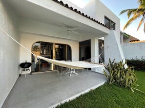 Eine moderne Außenpatio mit einer Hängematte, einem Grill und einer Glastür zu einem Innenbereich.