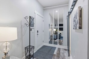 A hallway with a white door, a black metal rack, and a grey carpet.