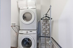 A laundry area with stacked washing machines and a drying rack.
