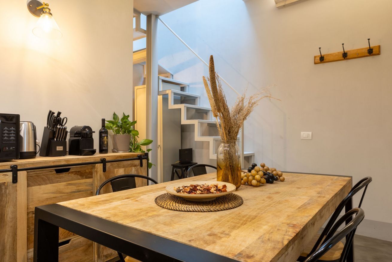 Una cucina moderna con un piano di lavoro in legno, una macchina per caffè e un vaso con piante essiccate.