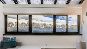 Ein Zimmer mit großem Fenster und Blick auf eine verschneite Landschaft.