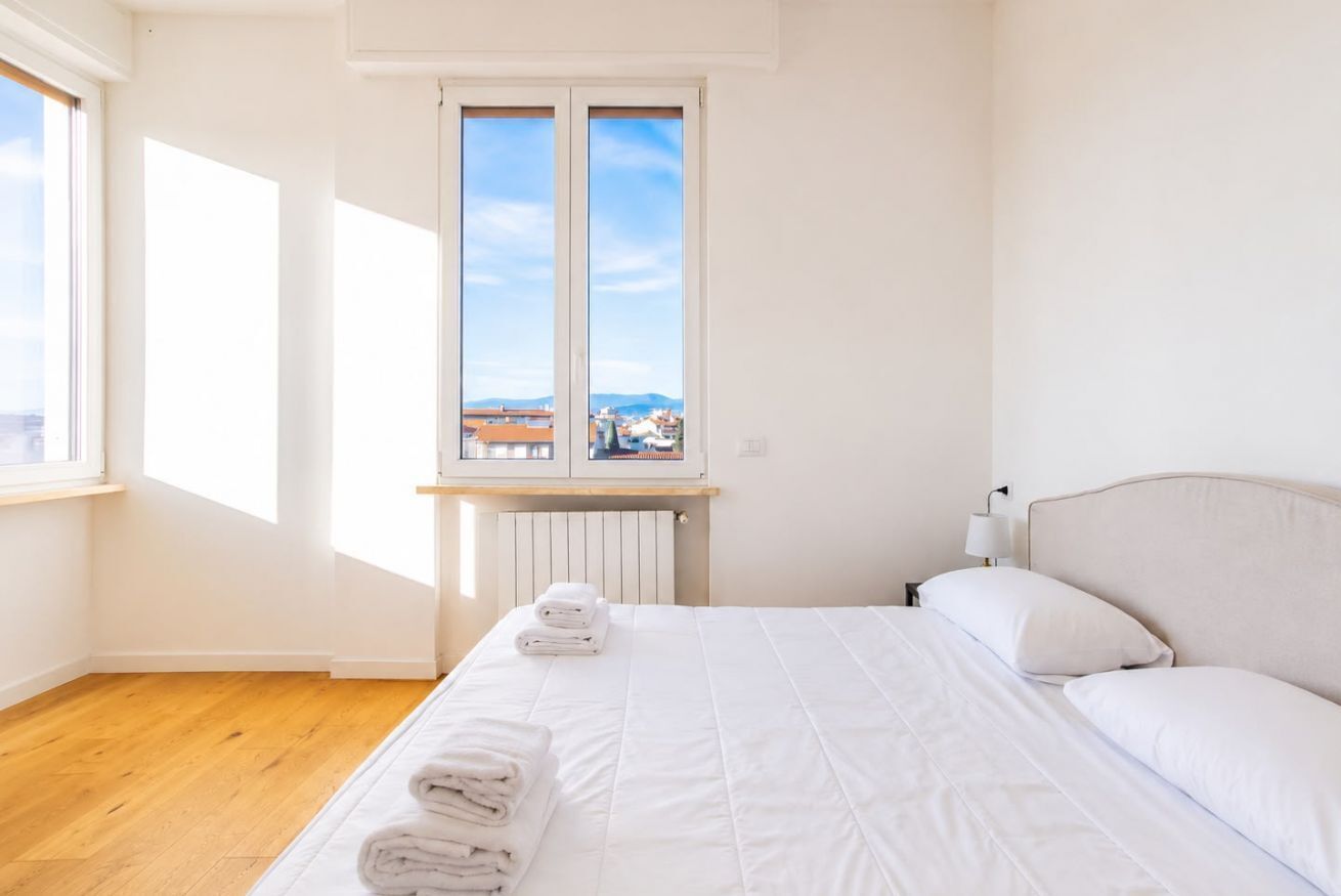 Une chambre à coucher avec un lit, une fenêtre, un radiateur et une vue sur la ville.
