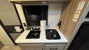 A compact kitchen with a stove, sink, and a small countertop. - Coleman (Oglethorpe County)