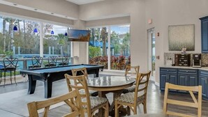 A modern kitchen with blue cabinets, stainless steel appliances, and a pool table in a spacious dining area with large windows. - Walking Distance to Boutique Shops, Private Garage (Westchase)