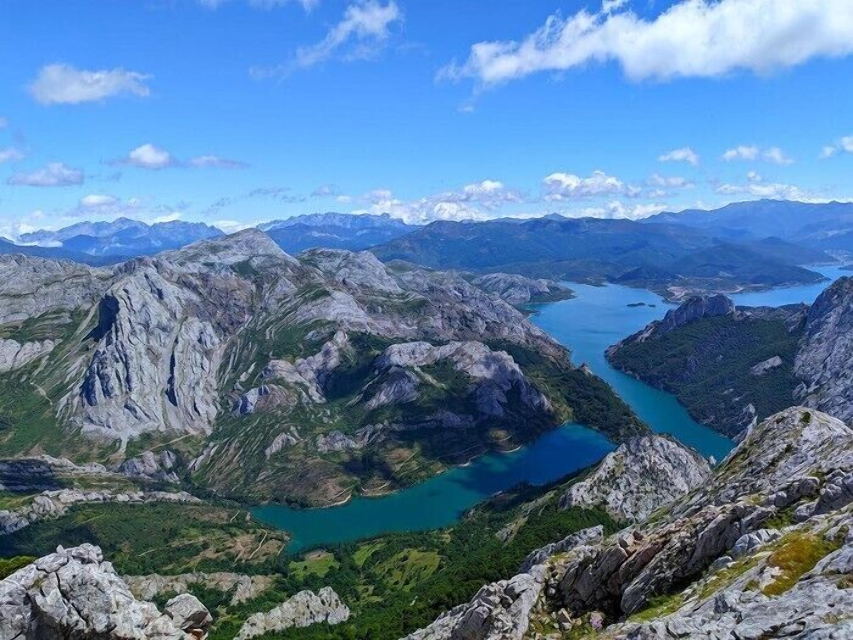 A mountainous landscape with rugged terrain and a turquoise lake.