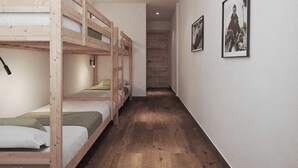 A narrow hallway with bunk beds on one side and framed pictures on the wall. - My Rooms Hostel Las Salas. Albergue (Las Salas)