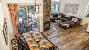 A dining area with a wooden table set for six, a stone fireplace, and a cozy seating area with a sofa and armchairs. - Snowcreek | Mtn Views | Fireplace | Loft (Mammoth Lakes)