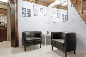 Ein Zimmer mit zwei schwarzen Ledersesseln, einem kleinen weißen Tisch mit einer Pflanze und einer Wand mit gerahmten Bildern.