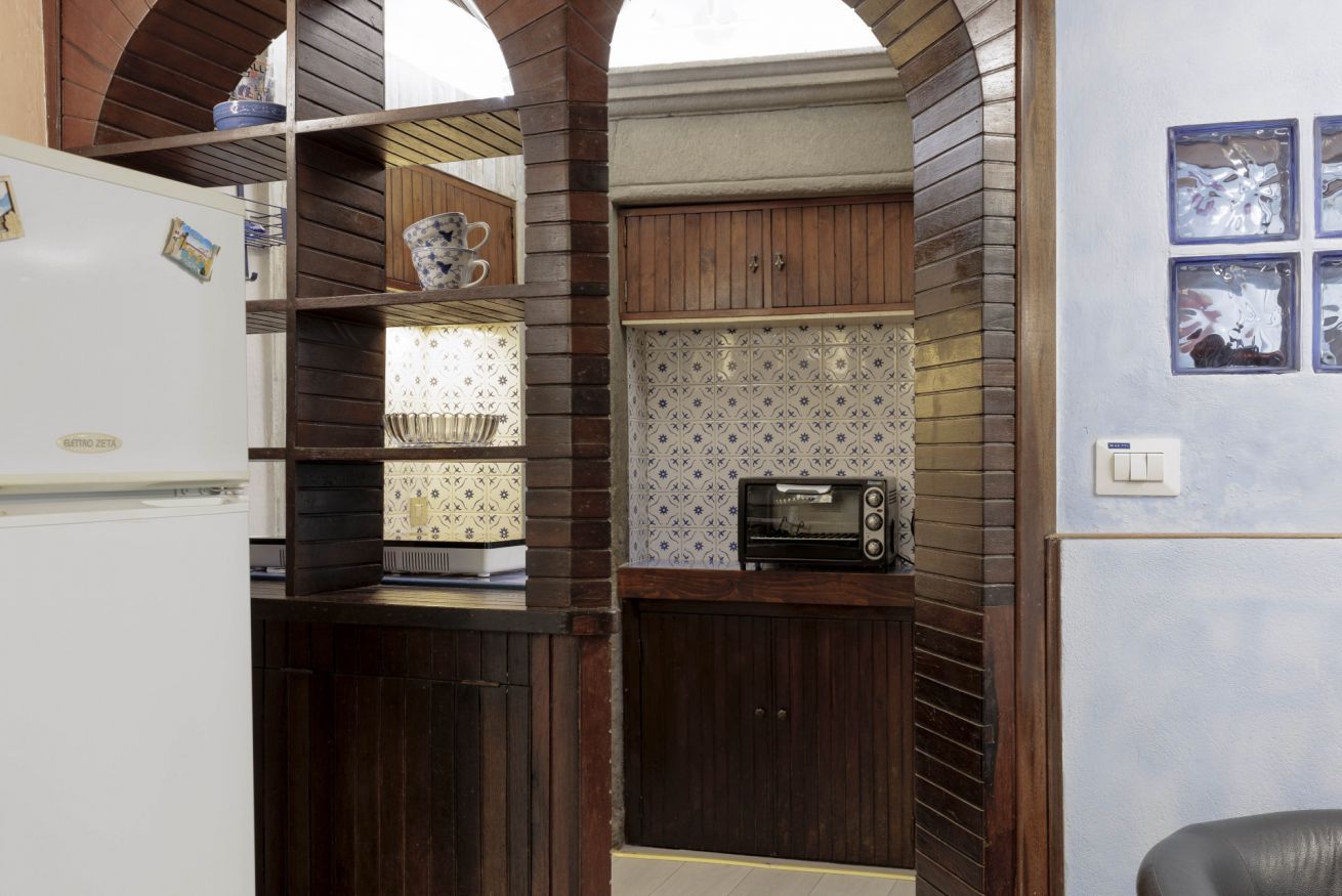 A compact kitchen with wooden cabinets, a built-in microwave, and a small countertop.