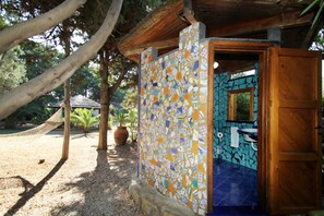 Ein rustikales Badezimmer im Freien mit Mosaikfliesen und einer Holztür.