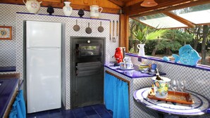 A rustic kitchen with a refrigerator, oven, and a window overlooking greenery. - Boutique Villa is an exclusive-use property located along the Tyrrhenian coast, nestled in a pine forest overlooking the sea.The main part of the villa consists of three charming cottages. Inside, you’ll find two bedrooms (one double and one twin), a b (Marina di Caronia)