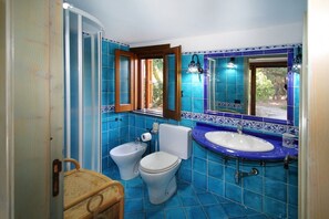 Ein Badezimmer mit blauen Fliesen, einem weißen Waschbecken, einer weißen Toilette und einem Bidet.