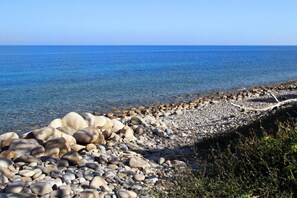 Une côte rocheuse bordée d’une eau d’un bleu limpide, avec un horizon lointain.