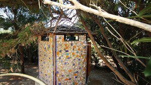 Ein kleines, farbenfrohes Gebäude mit Mosaikfliesen, umgeben von Bäumen.