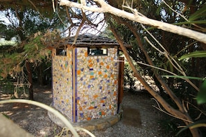 Ein kleines, farbenfrohes Gebäude mit Mosaikfliesen, umgeben von Bäumen.