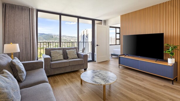 A modern living room with a sofa, a coffee table, and a TV. - Warm and Cozy Getaway 1BR w/ parking (Honolulu)