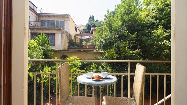 Un balcon avec des fauteuils en osier, une petite table ronde et un croissant.