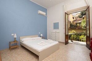 Een slaapkamer met een bed, nachtkastjes, een kast, een airconditioningapparaat, een raam met uitzicht en een balkon.