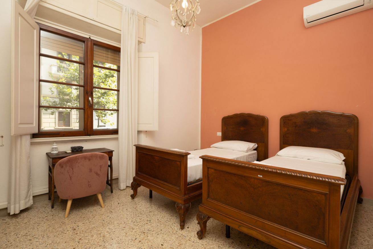 A bedroom with two wooden beds, a small desk, and a chair.