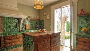 A kitchen with green tiles, wooden cabinets, and a central island. - Casa Limonella - Maison 12 pers avec piscine (Fontvieille)