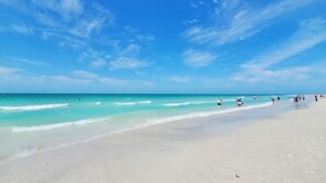 A wide sandy beach with clear turquoise water and a few people in the distance. - Charming 3-bedroom vacation home near Siesta Key (Sarasota)