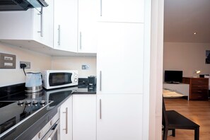 A modern kitchen with white cabinets, a black countertop, and stainless steel appliances including a microwave, coffee maker, and kettle. - Prime Clerkenwell Studio | 2 Mins to Farringdon - Pass the Keys (London)