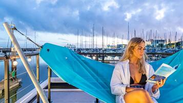 A person sitting on a hammock by a marina with boats in the background.