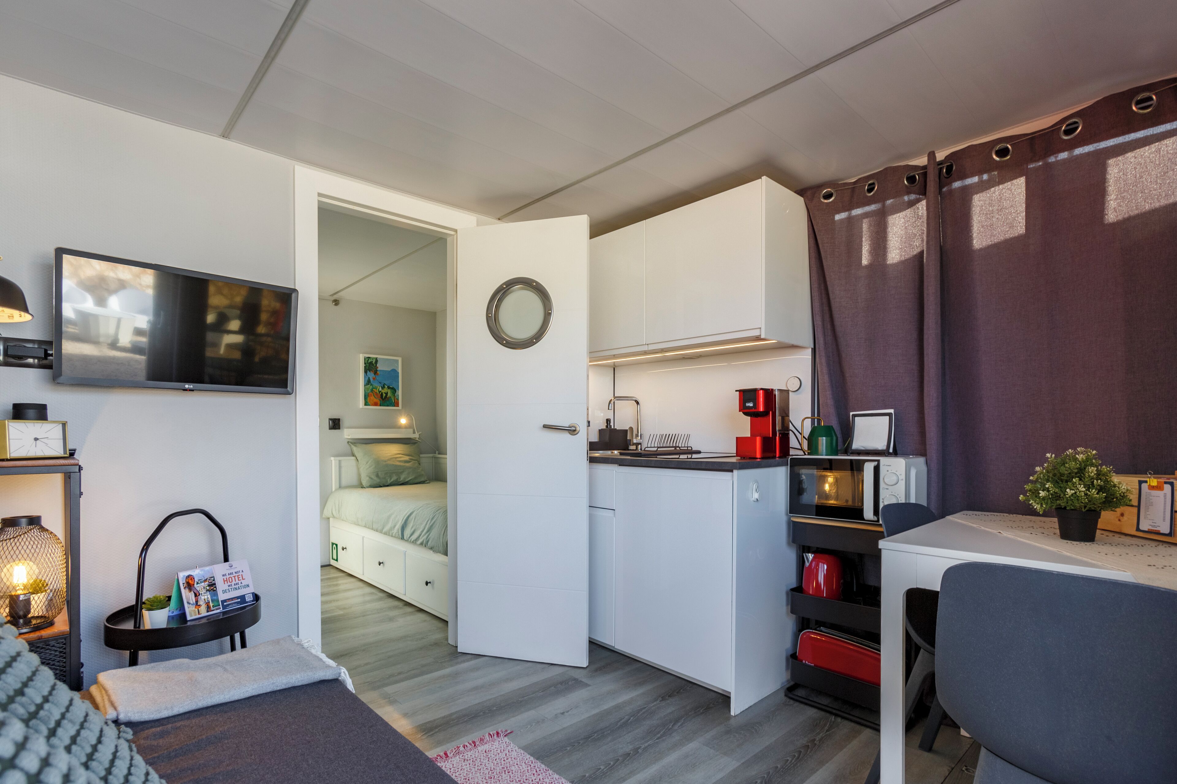 A compact room with a kitchenette, a bed, a TV, and a small dining area.