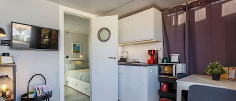 A compact room with a kitchenette, a bed, a TV, and a small dining area.