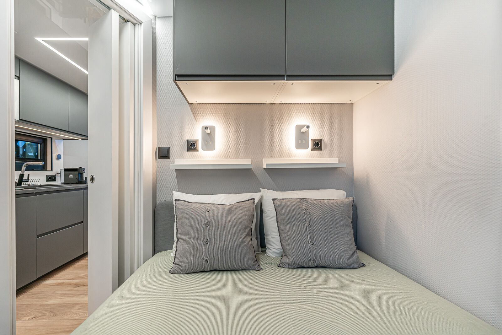 Een moderne slaapkamer met een bed, twee nachtkastjes en een ingebouwde televisie.