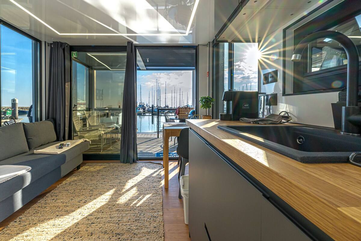 A modern kitchen with a wooden countertop and a view of the marina through large windows.