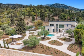 A modern two-story house with a swimming pool, surrounded by landscaped gardens and a mountainous backdrop. - Villa Cypressa by Villa Plus (Lefkada City)