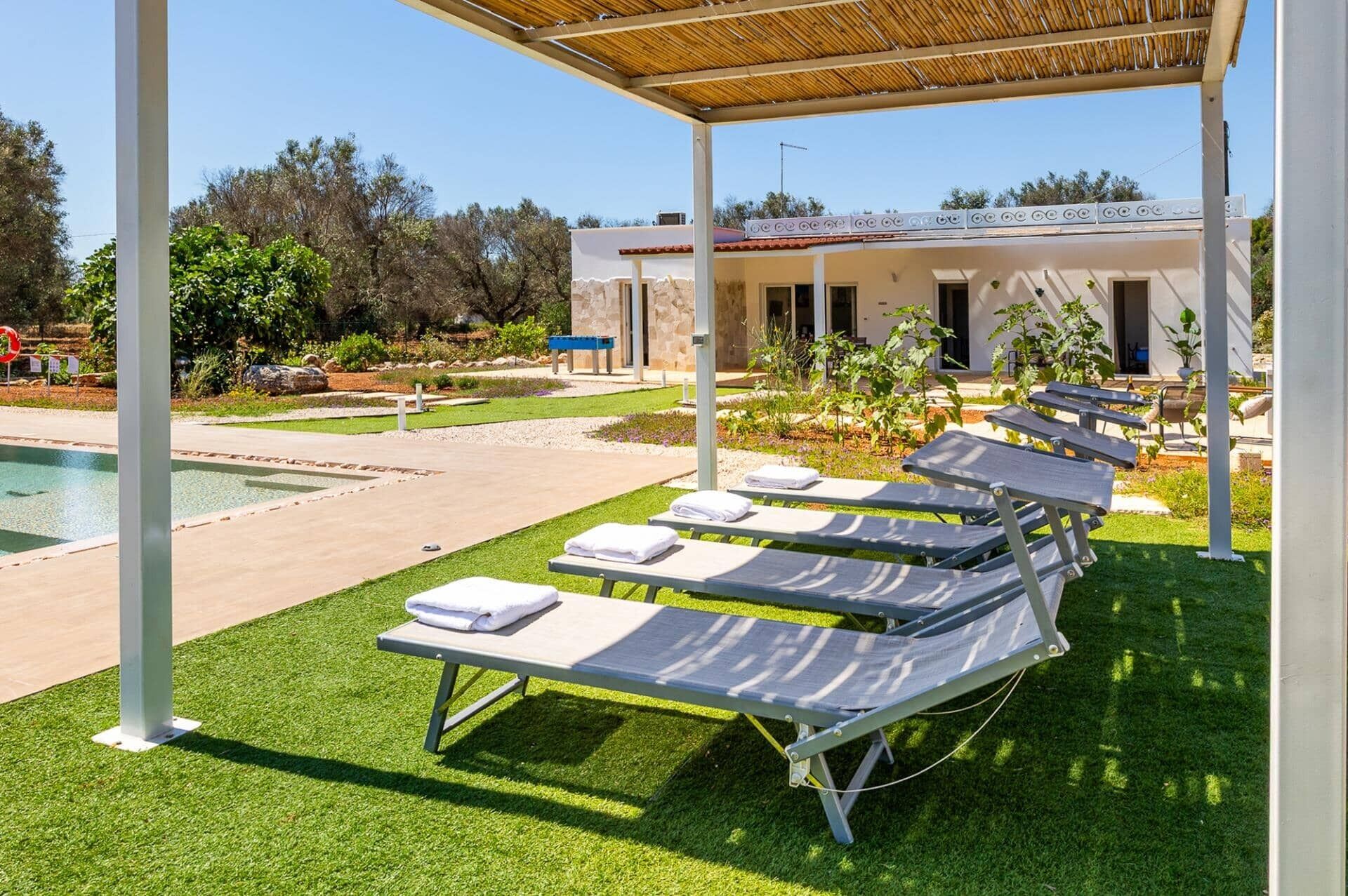 A poolside area with lounge chairs and a covered seating area.