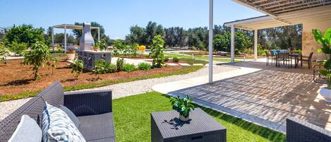 An outdoor patio area with wicker furniture, a grill, and a covered seating area.