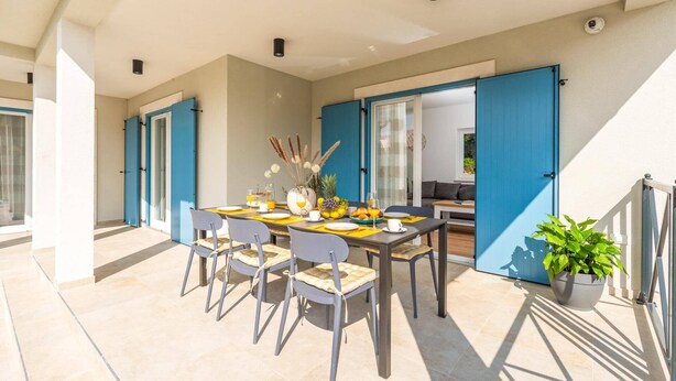 A sunlit patio with a dining table set for two, surrounded by chairs. - Villa Azurno by Villa Plus (Juršići)