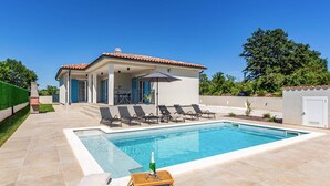 A swimming pool with lounge chairs, a table with chairs, and a bottle of champagne on a tray. - Villa Azurno by Villa Plus (Juršići)