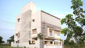 A modern multi-story building with a flat roof and a balcony on the second floor. - The Residence 267 Homestay (Mysore)