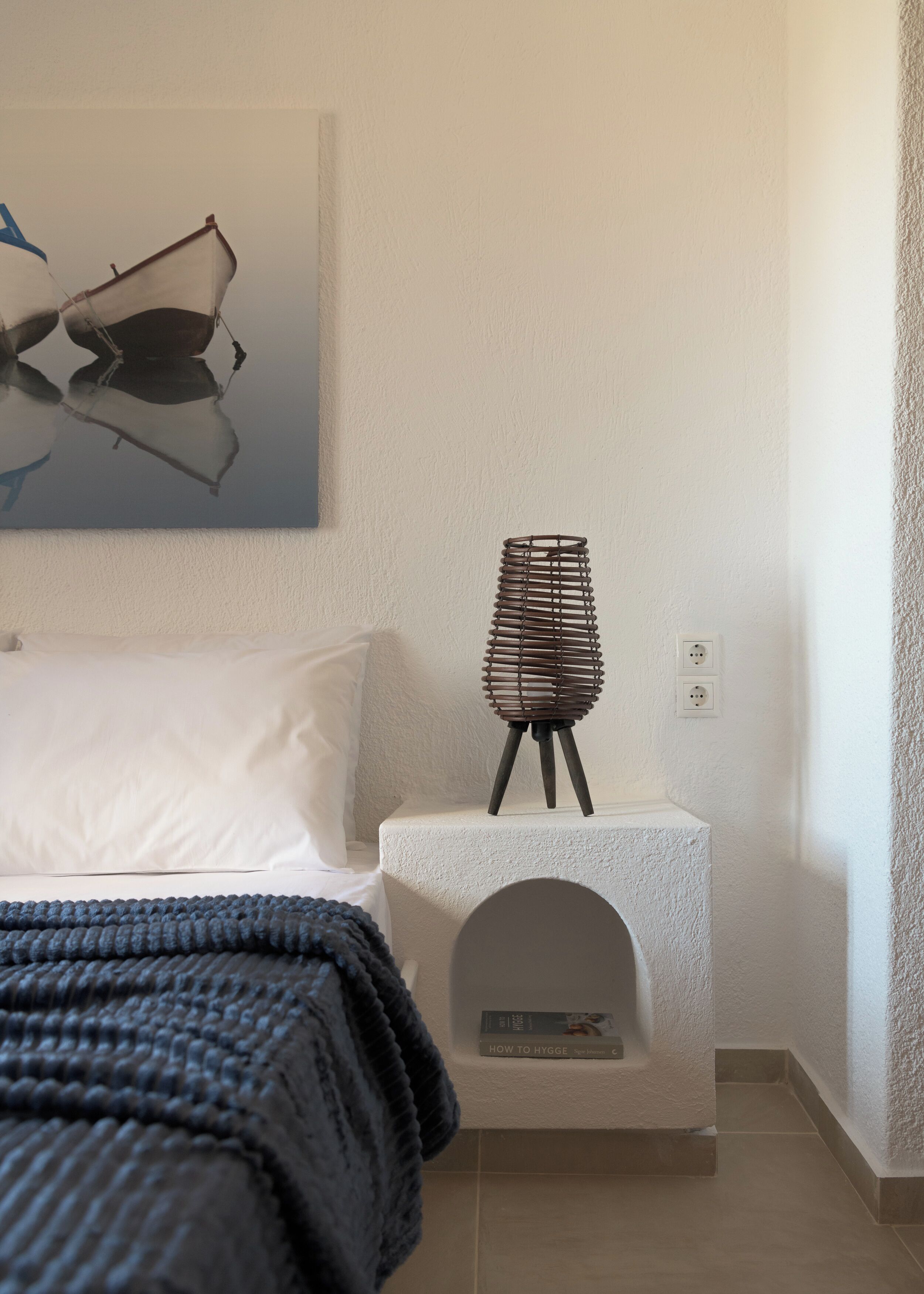 Une chambre à coucher avec un lit, une table de chevet avec une lampe et une œuvre d’art accrochée au mur.