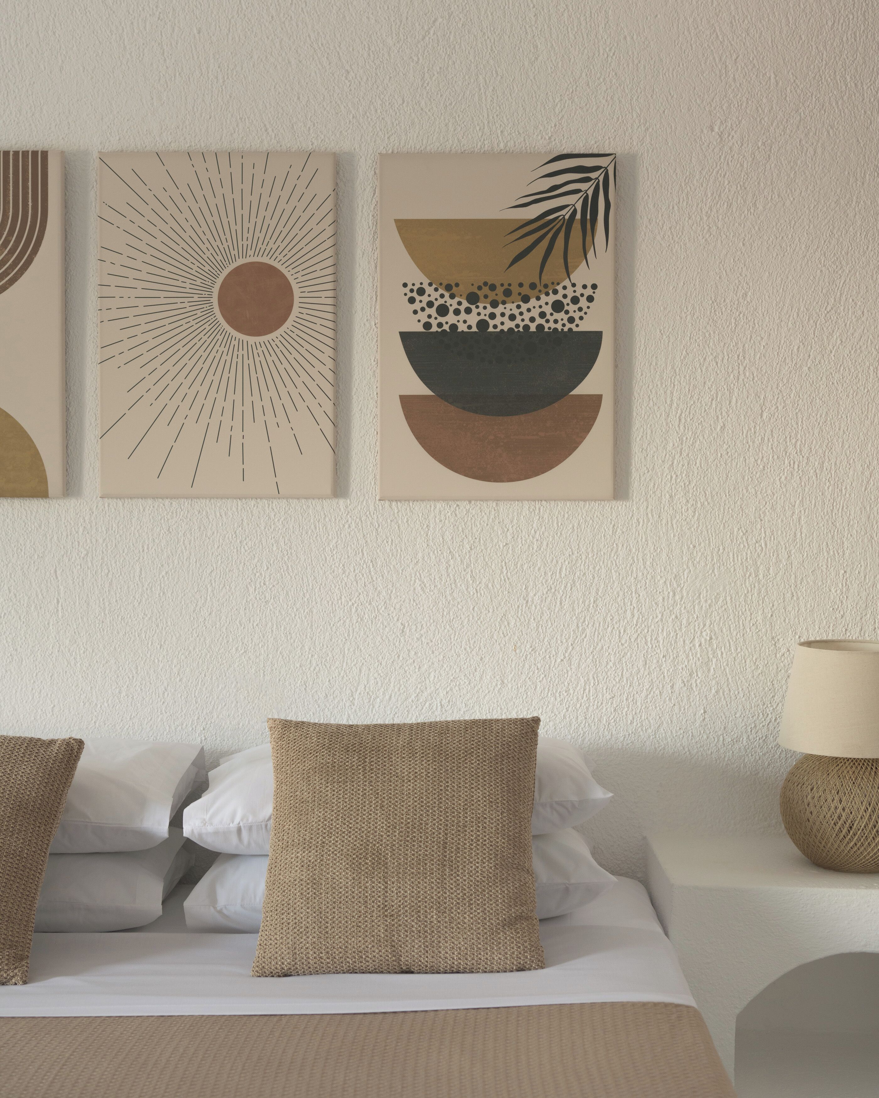Une chambre à coucher avec un lit, des oreillers, une table de chevet et des œuvres d’art murales.