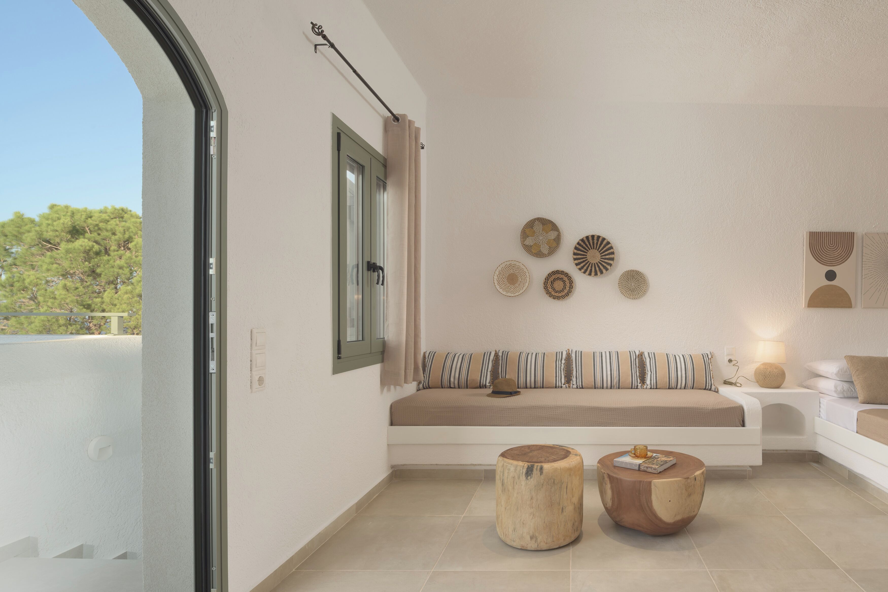 Una sala de estar moderna con un sofá, dos taburetes de madera y decoración en la pared.