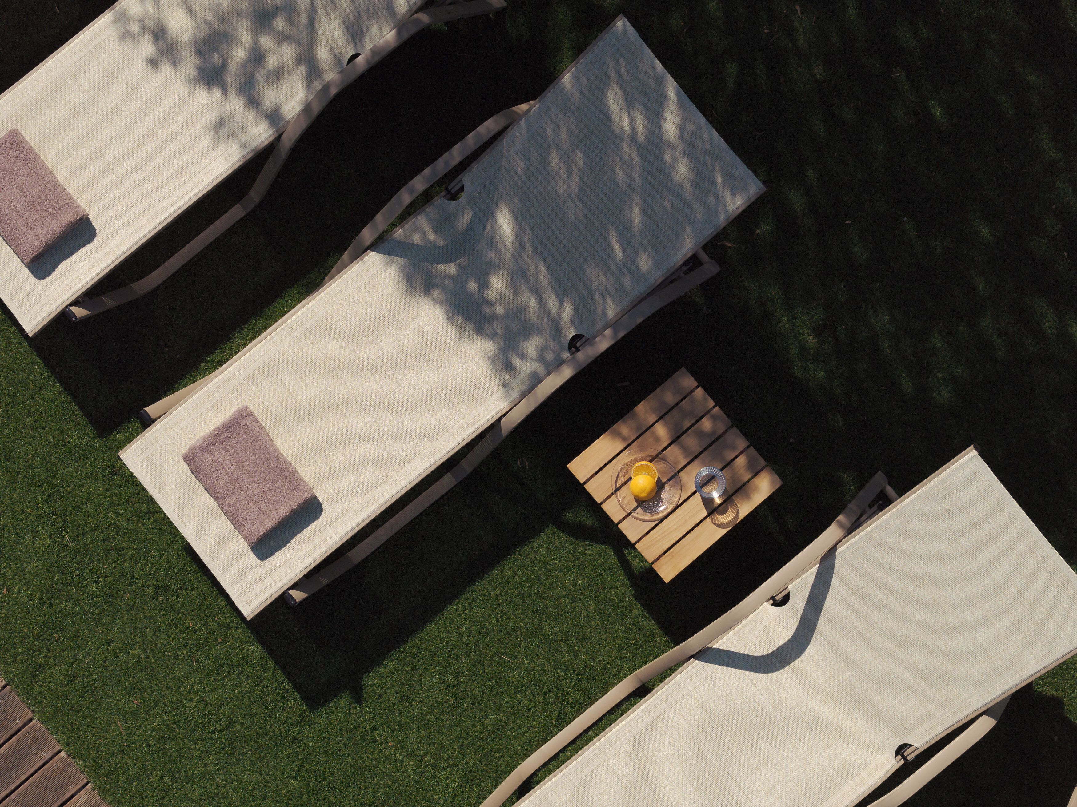 An aerial view of a poolside area with lounge chairs and a small table with a drink.