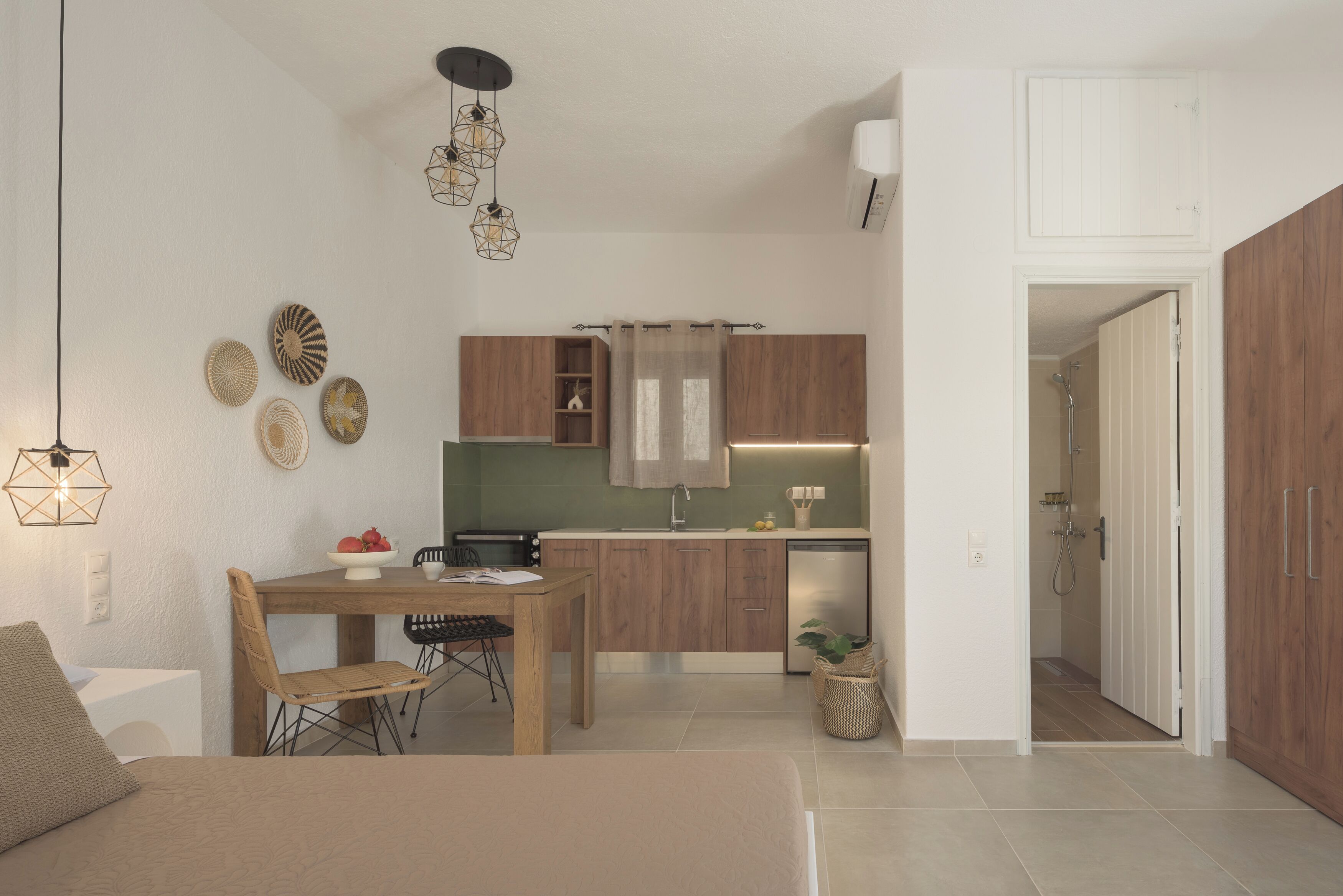A compact living space with a kitchenette, a dining area, and a shower area.
