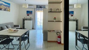 A modern living room with a dining area, a sofa, a coffee table, and a fireplace. - Apartment with terrace Etna and sea view near central station (Catania)