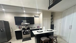 A modern kitchen with a central island, black cabinets, and a microwave. - Rainbow Retreat near the heart of kingston (Kingston)