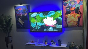 A living room with a flat-screen TV mounted on the wall, surrounded by artwork, a coffee table, and a sofa with colorful cushions. - Rainbow Retreat near the heart of kingston (Kingston)