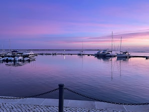 A marina with boats docked, calm water, and a clear sky.