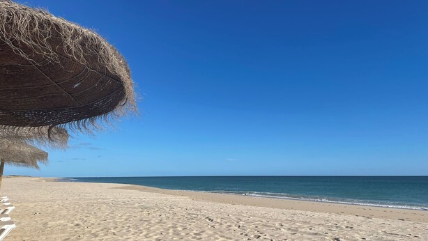A beach with a thatched umbrella and footprints in the sand. - CASA JO – a beautifully renovated, comfortable fisherman's cottage in the historic center of Olhão (Olhão)