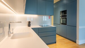 A modern kitchen with a white countertop, blue cabinets, and stainless steel appliances. - FLH Heart of Rossio Apartment III (Lisboa ciudad)