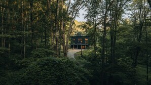 A modern house surrounded by dense forest. - Luxury Cabin | Hot Tub + Forest Views (Logan)